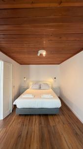 a bedroom with a bed with a wooden ceiling at Refúgio das Marés in Ponta Delgada