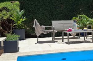 a chair and a table next to a pool at Le Voyageur in Sainte-Marie