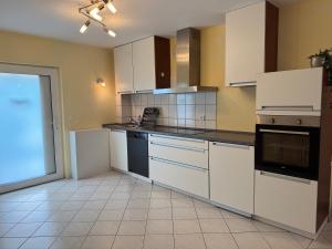 a large kitchen with white cabinets and black appliances at Ferienwohnung Naunheim, ebenerdig, Smart TV in Wetzlar
