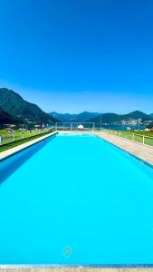 a large blue swimming pool with mountains in the background at L4K3 Luxury Apartment - Lake View, Free Pool, Balcony, 50 m to Lake & Historic Center, 90 m2 in Pisogne