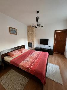 a bedroom with a bed with a red comforter and a television at Casa de Vacanta Sarinasuf in Sarinasuf