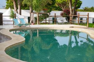 a swimming pool with two lawn chairs at CALMA TIPI Glamping con piscina en Chiclana in Chiclana de la Frontera