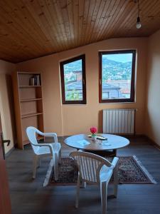 a room with a table and chairs and two windows at Apartman Mickey in Sarajevo