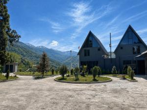a building with two pointed roofs with mountains in the background at Casa Verde&Mare in Sharabidzeebi