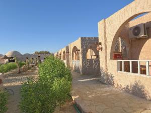 a building with a stone wall with a fence at Adrartaziry in Siwa