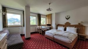 a hotel room with two beds and a window at Apartments Alpenroyal Arabba - Check-in at Garni Royal in Arabba
