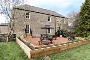 a stone building with two picnic tables and umbrellas at Redesdale Arms in Otterburn