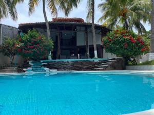 a swimming pool in front of a house with palm trees at Monarca Village in La Libertad