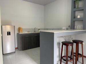 a kitchen with a refrigerator and two bar stools at Monarca Village in La Libertad