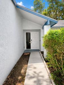 a white house with a door and a sidewalk at Cozy Tampa Home in Tampa