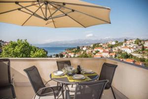 a table with chairs and an umbrella on a balcony at Apartments Marijin Dvor in Splitska