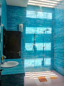 a blue bathroom with a shower and a sink at White Villa Goyambokka - Private Pool Villa in Tangalle