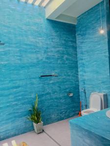 a blue bathroom with a toilet and a blue wall at White Villa Goyambokka - Private Pool Villa in Tangalle