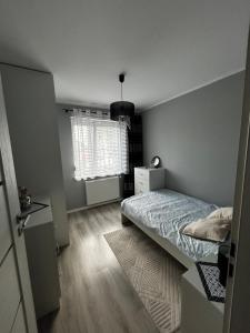 a small bedroom with a bed and a window at Apartament w Dolinie Baryczy in Milicz +6 photos