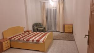 a bedroom with a bed and a chair and a window at Orges Apartament in Struga