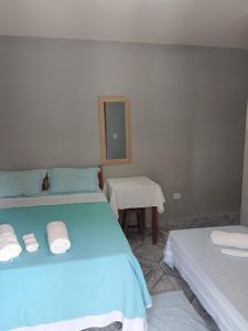 a room with two beds and a table and a mirror at Trindade Flat Azulmar in Trindade