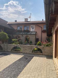 a house with a brick wall and a stone walkway at Penzion Kohout in Nýrsko +5 photos