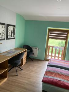 a bedroom with a bed and a desk and a window at Penzion Kohout in Nýrsko
