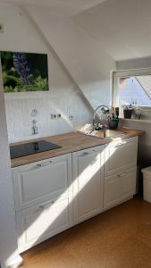 a kitchen with white cabinets and a sink and a window at Fischerhaus Herstelle in Beverungen