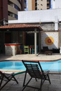a pair of chairs sitting next to a swimming pool at Rô Hostel Cabo Branco in João Pessoa