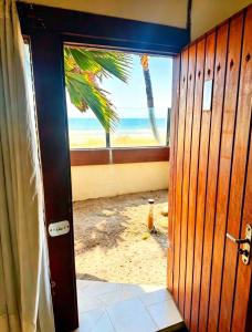 an open door to a beach with a palm tree at Beachfront suite right on the sand in Cabo Frio +15 photos