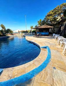 a swimming pool in a resort with chairs and a gazebo at Beachfront suite right on the sand in Cabo Frio