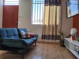 a living room with a blue couch with two stuffed animals on it at Casa hogareña Pequeña in Ica