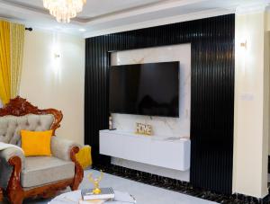 a living room with a large tv and a chair at Godly Homes 5km frm Weiteithie! 4BR mdrn home in Ruiru