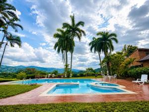 a swimming pool with palm trees and a house at ANAPOIMA Toscana in Anapoima