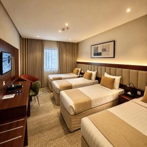 a hotel room with three beds and a desk at Park Elite Hotel - فندق بارك إيليت in Mecca