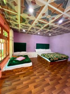 two beds in a room with purple walls and wooden floors at Saleem Resort in Skardu
