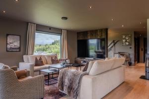 a living room with two couches and a large window at Stort hus med jaquzzi in Geilo