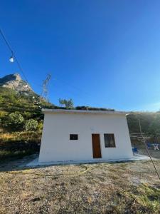 a small white house with a hill in the background at Bujtina Dalmacia 2 in Shkodër