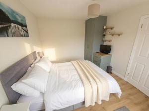a bedroom with a white bed and a television at Cromlech Cottage in Portnoo