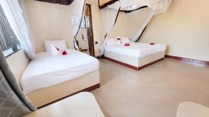 two beds in a room with white sheets and red roses at Meremeta Lodge in Utende