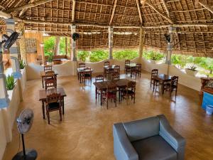 a restaurant with tables and chairs and a couch at Meremeta Lodge in Utende