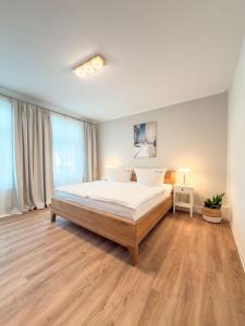 a bedroom with a bed with white sheets and wood floors at Villa Victoria in Binz