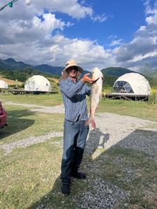 a man in a hat holding a fish at Chadir yurd glamp in İsmayıllı