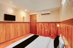 a bedroom with a bed and a tv on the wall at HOTEL O SAFFRON in Meerut