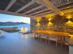 a dining room with a table and a stone wall at Farous seaside sunset villa II in Antiparos