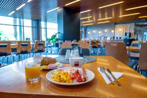 a table with a plate of breakfast food and a glass of orange juice at Hotel Ledňáček in Ostrava +27 photos
