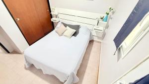 a small bedroom with a bed with white sheets and pillows at AltaMar in Playa Unión