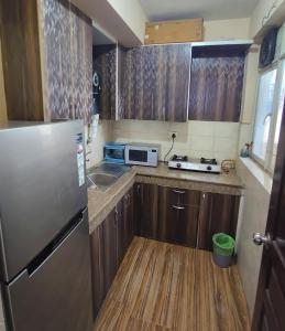 a small kitchen with a refrigerator and a sink at 2BHK 65TV,FullyAC,family,Unmarried Couple,WFO Friendly peacefull place in Noida