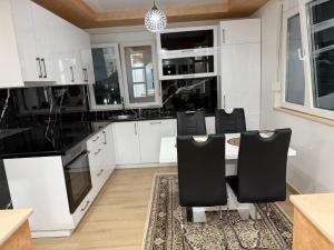 a kitchen with white cabinets and a table and chairs at Lux apartment in Dobra Voda +11 photos
