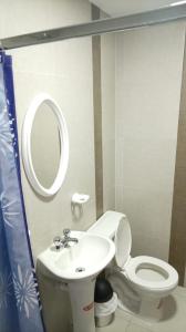 ein Badezimmer mit Waschbecken, Toilette und Spiegel in der Unterkunft Hotel Jomaley in Loja