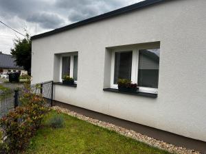 a white house with two windows with flowers in them at Apartmán Buky in Mladé Buky