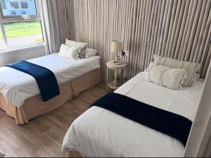 two beds in a small room with a window at Waterside Lodge, Weybourne, Holt in Weybourne
