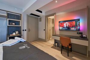 a bedroom with a bed and a desk with a tv on the wall at Ramses Hotel İzmir in İzmir