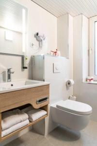a white bathroom with a toilet and a sink at Astoria Hotel Essen in Essen