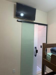 a flat screen tv on the wall of a bedroom at Pousada SMART AIRPORT 10 min GRU in Guarulhos